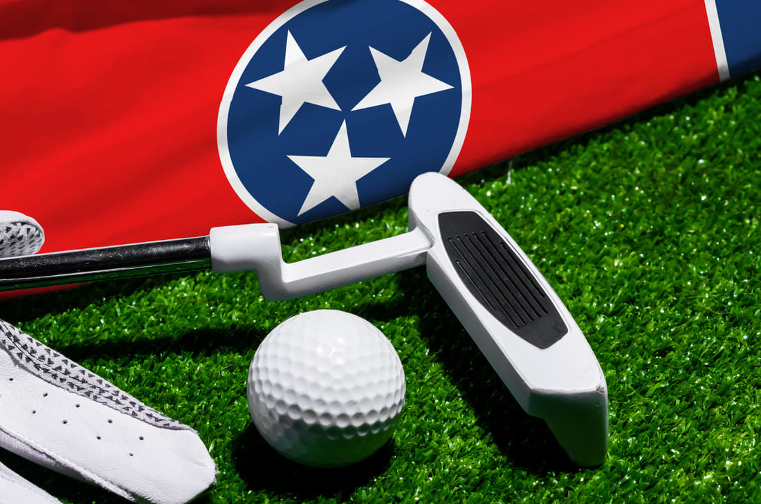 Golf club and balls next to a cart bag with a Tennessee flag 